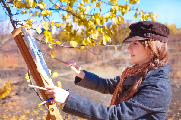 Girl with brushes paints on white paper — Stock Photo, Image