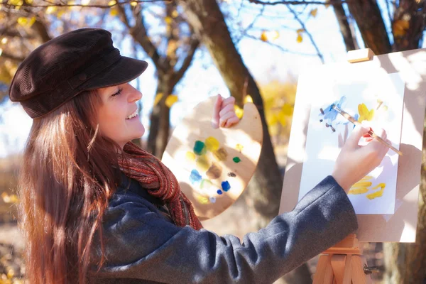 Flicka med palett i hand skissar på papper — Stockfoto