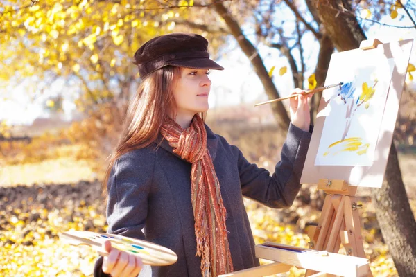 Girl with palette in hand sketches on paper — Stock Photo, Image