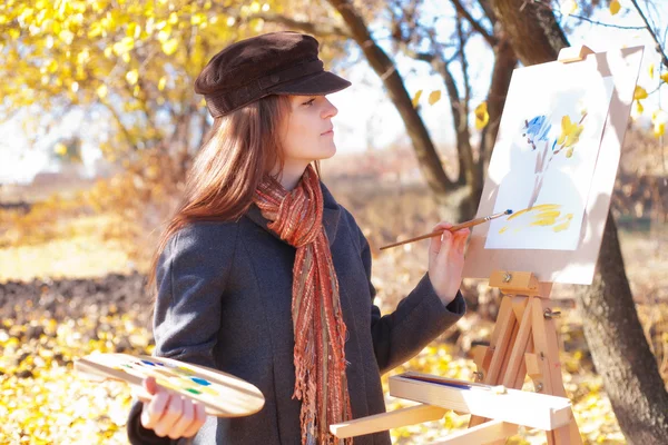 Girl with palette in hand sketches on paper — Stock Photo, Image