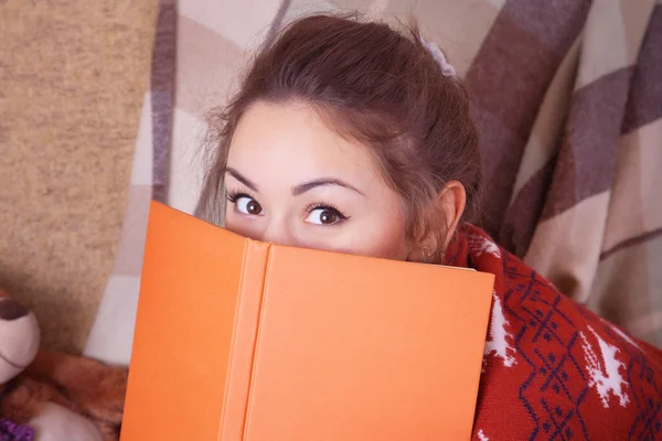 Linda chica en el sofá con un libro —  Fotos de Stock