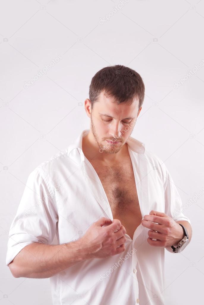Young man with beautiful face, muscular torso, dressed in white unbuttoned shirt