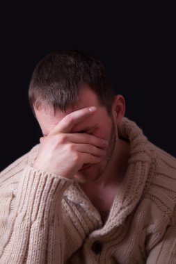 Üzgün adam yüzünü bir el ile kapsar