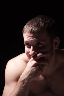 Gömleksiz adam yüzüne elini tutarak görüntüsünü