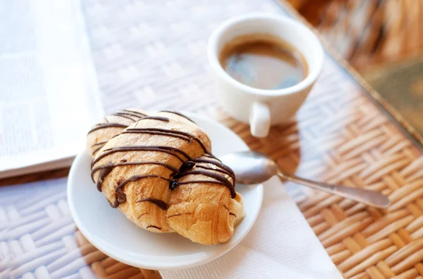 Tasse Kaffee und ein Croissant auf dem Tisch — Stockfoto