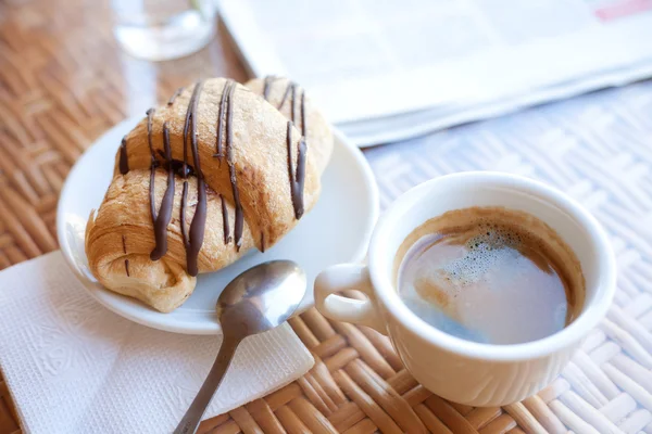 Tasse Kaffee und ein Croissant auf dem Tisch — Stockfoto