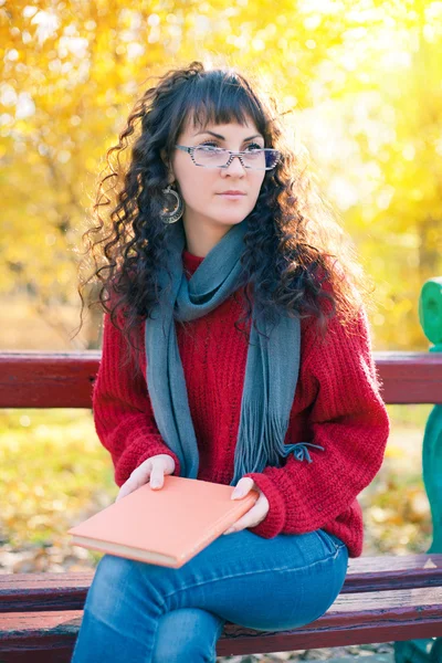 Bir kitap parkta oturan genç kadınla — Stok fotoğraf