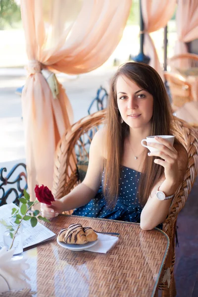 Beautiful young woman with cup of at a cafe — Stock Photo, Image