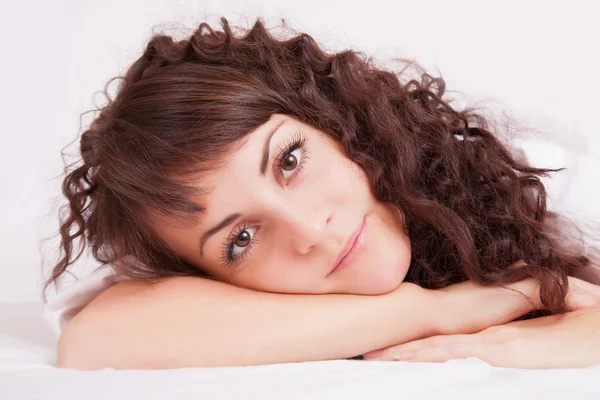 Beautiful woman in white shirt lying on a bed — Stock Photo, Image