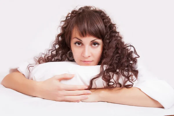 Krásná žena v bílé košili, ležící na posteli — Stock fotografie