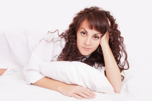 Mooie vrouw in wit overhemd liggend op een bed — Stockfoto