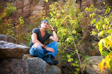 Doğada bir taş üzerine oturan adam aittir