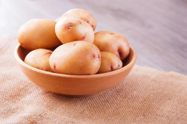 Close-up van ruwe aardappelen in kom op houten achtergrond, — Stockfoto