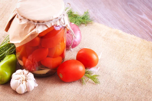 Tomates marinados en frascos con especias y verduras sobre una mesa — Foto de Stock