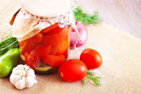Tomates marinados en frascos con especias y verduras sobre una mesa — Foto de Stock