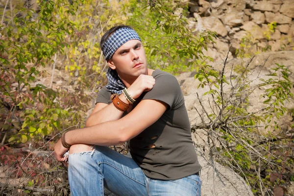 Man rests in the nature sitting on a stone — Stock Photo, Image