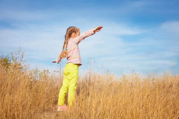Gökyüzüne karşı duran parlak giysili küçük kızı — Stok fotoğraf