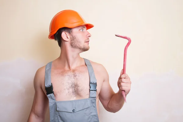Man in overalls with a tool for dismantling — Stock Photo, Image