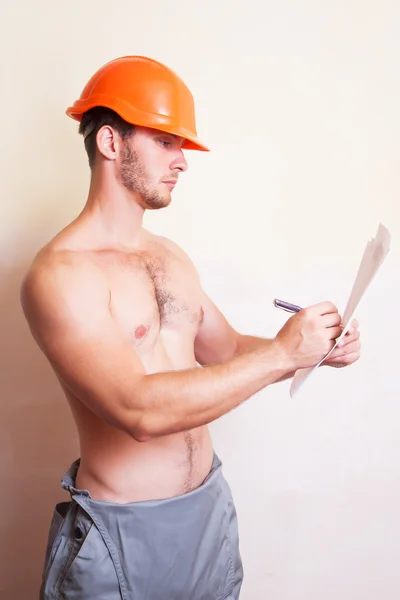 Man in a helmet writes on paper — Stock Photo, Image