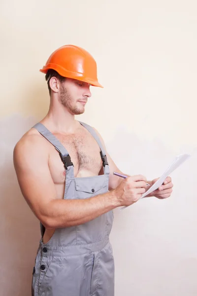 Man in a helmet writes on paper — Stock Photo, Image