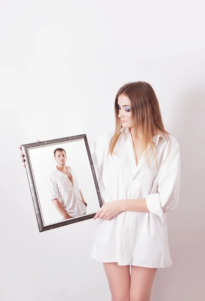 Jeune femme en chemise blanche tenant un portrait — Photo