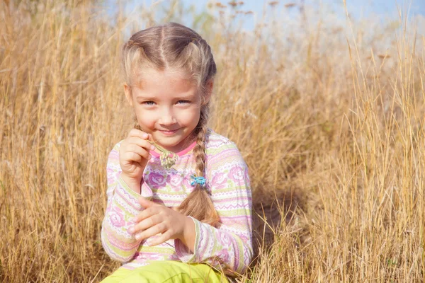 Chica alegre en la naturaleza con una hoja de hierba en las manos — Foto de Stock