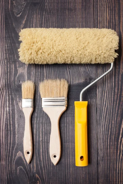 Paint brushes and roller on old wooden background — Stock Photo, Image