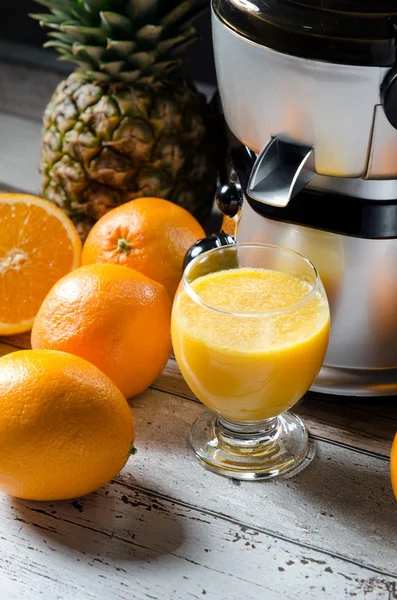 Juicer och orange juice i glas på trä skrivbord — Stockfoto