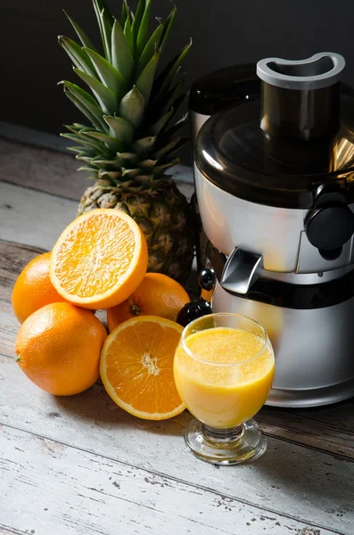 Juicer och orange juice i glas på trä skrivbord — Stockfoto