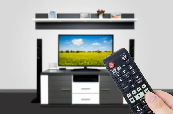 Tittar på TV i moderna TV-rum. Hand som håller fjärrkontrollen — Stockfoto