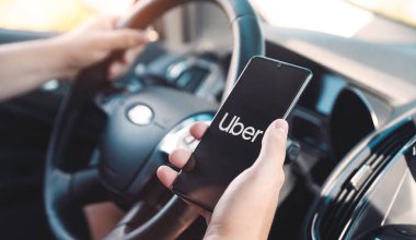 Wroclaw, Polonya - 25 AUG 2020: Uber sürücüsü akıllı telefonu arabada tutuyor. Uber ubran taşımacılığı için ekonomi hizmetini paylaşıyor.