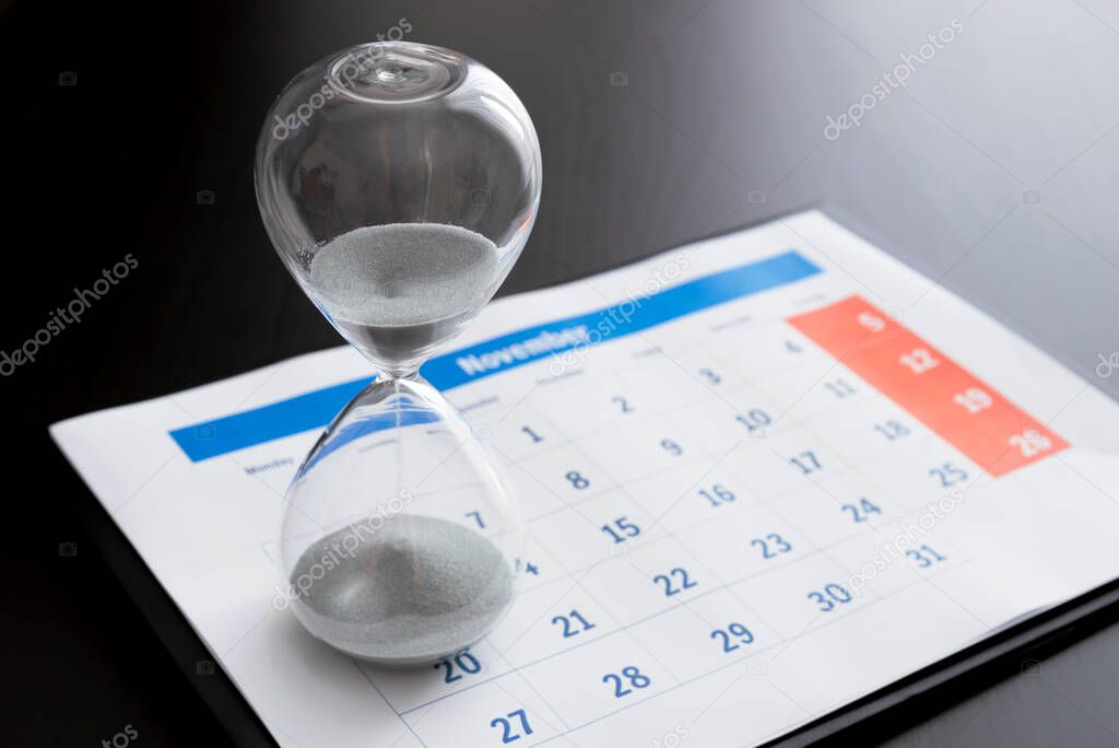 Time passing concept, time slipping away. Hourglass and the calendar