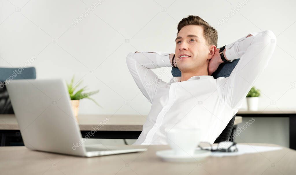 Businessman relaxing in office after hard working day. Happy employee sitting on a chair in the office