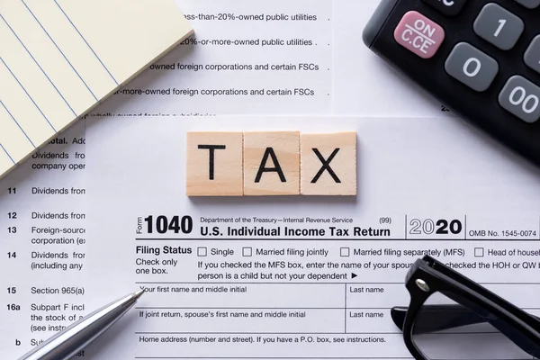 木製のタイルで作られた税金の単語 机の上にアメリカの税務申告書 事業所得税の概念 — ストック写真