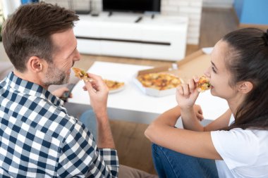 Pizza yerken televizyon izleyen bir çift. Evde boş vakit geçirmek.
