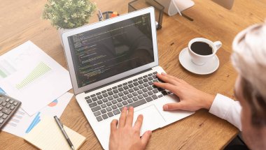 Programcı ofiste kod üzerinde çalışıyor. Dizüstü bilgisayarda çalışan adam.