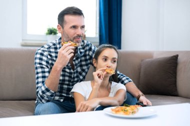 Pizza yerken televizyon izleyen bir çift. Evde boş vakit geçirmek.
