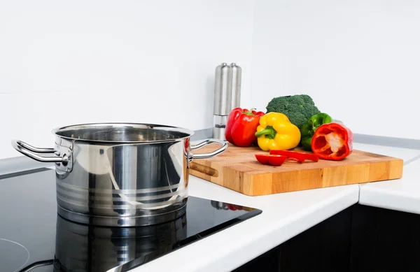 Maceta y verduras en cocina moderna con estufa de inducción —  Fotos de Stock