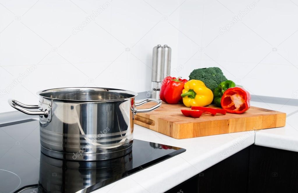 Pot and vegetables in modern kitchen with induction stove