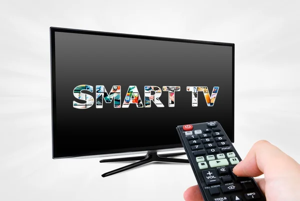 Mano con mando a distancia con el objetivo de dispositivo moderno Smart TV — Foto de Stock