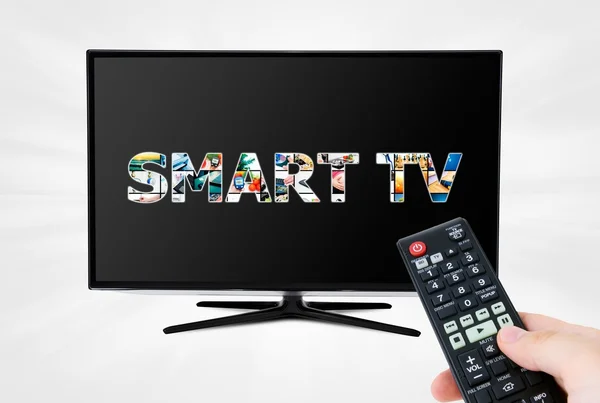 Mano con mando a distancia con el objetivo de dispositivo moderno Smart TV — Foto de Stock