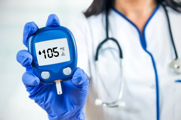 Closeup samenstelling van vrouw arts houden glucometer. — Stockfoto