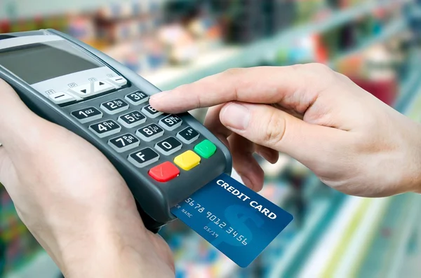 Mão com cartão de crédito deslizar através do terminal para venda em superma — Fotografia de Stock
