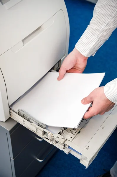 Man puts the paper in a laser printer — Stock Photo, Image
