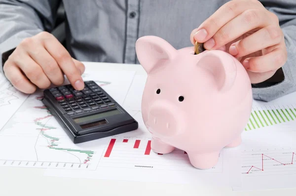 Un hombre poniendo moneda en una alcancía. Ahorro de dinero concepto —  Fotos de Stock