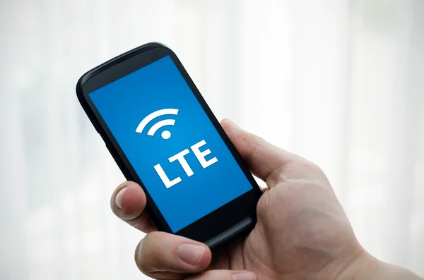 Mão segurando telefone celular com tecnologia de internet rápida LTE — Fotografia de Stock