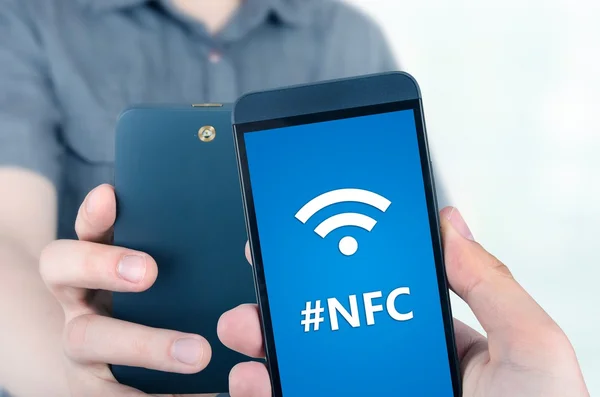 Mão segurando smartphone com tecnologia NFC perto de campo communi Imagens De Bancos De Imagens