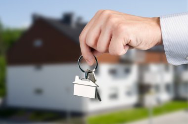 Man hand holding keys with to new house clipart