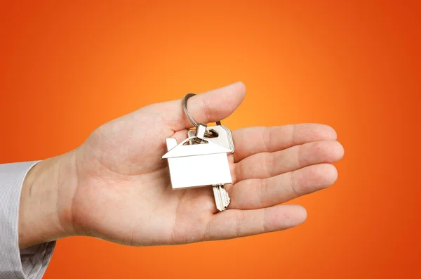 Hombre mano sosteniendo llaves con a nueva casa —  Fotos de Stock