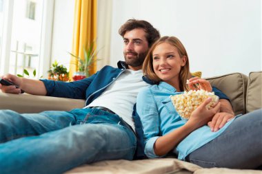 TV izlerken, bir koltukta evde patlamış mısır yemek çift